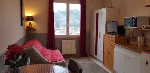 un salon avec une table et une fenêtre dans l'établissement Studio Albizia Lamalou les Bains, à Lamalou-les-Bains