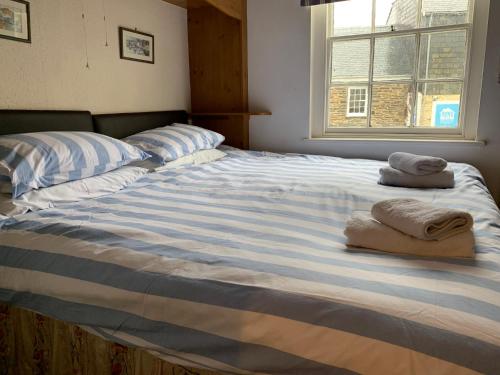 a large bed with two towels on top of it at Maypole Cottages No 10 Broad Street Padstow in Padstow