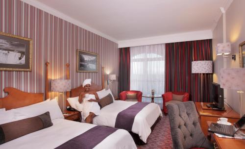 una camera d'albergo con due letti e un uomo seduto su un letto di Walmont at Graceland a Secunda