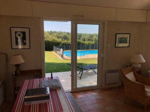 Cette chambre dispose d'une porte coulissante en verre offrant une vue sur la piscine. dans l'établissement Maison familiale avec piscine, à Pénestin