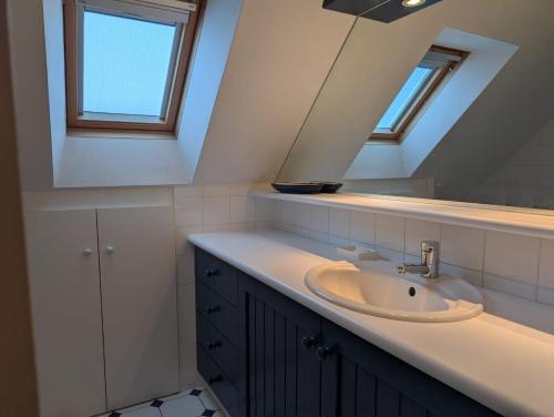 une salle de bain avec un lavabo et un miroir dans l'établissement Maison familiale avec piscine, à Pénestin