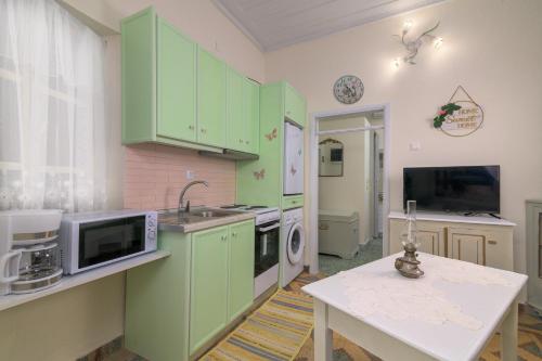 a kitchen with green cabinets and a white table at Kyramarias Village house in Malona Village