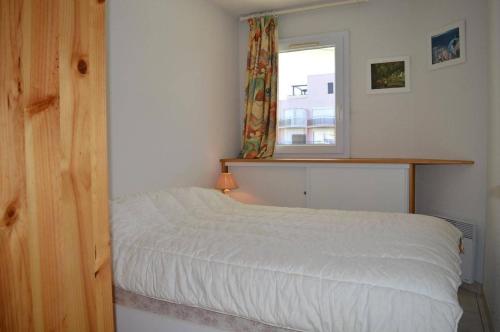 une chambre avec un lit blanc et une fenêtre dans l'établissement Appartement 2 pièces cabine 6 couchages SAINT CYPRIEN SC050-288A, à Saint Cyprien Plage
