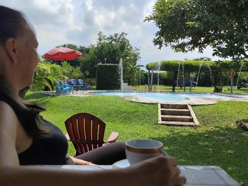 a woman sitting at a table in front of a pool at Villa Milena in Santa Helena