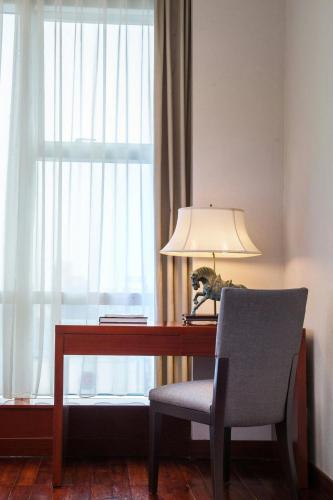 a desk with a lamp and a chair next to a window at The Mayflower, Jakarta-Marriott Executive Apartments in Jakarta