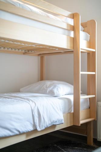 a bunk bed with white sheets and pillows on it at The Edgewater Suites - Cityscape in Namur