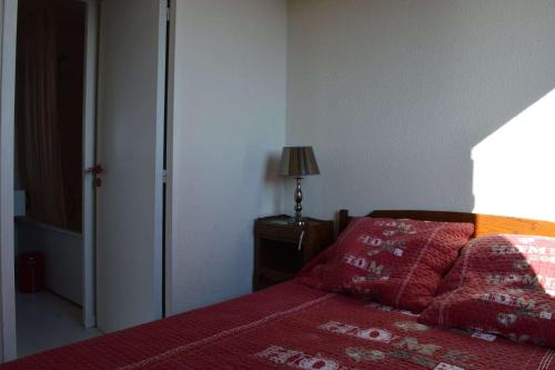 - une chambre avec un lit doté de draps rouges et d'une lampe dans l'établissement Appartement 2 pièces Saint Cyprien 5 personnes sc300-131, à Saint Cyprien Plage