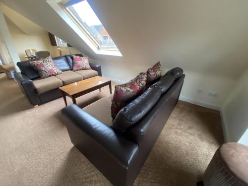 a living room with a leather chair and a couch at Macdonald Elmers Court Hotel in Lymington