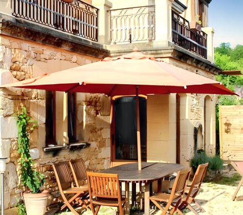 a table with an umbrella in front of a building at Maison conviviale à Saint-Cybranet avec piscine partagée in Saint-Cybranet
