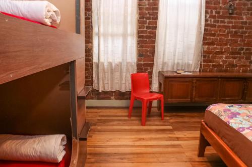 a room with a red chair and a bed and window at Blue House Youth Hostel in Quito