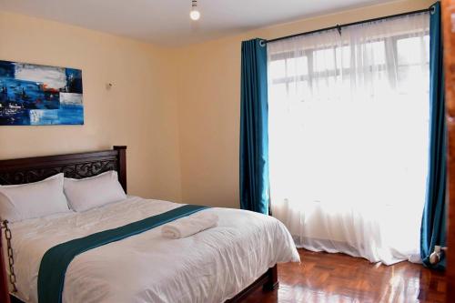 a bedroom with a bed and a large window at Riverside Spacious Haven in Nairobi