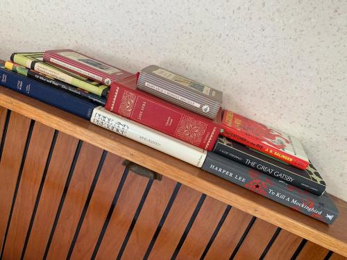 ein Stapel Bücher auf einem Holzregal in der Unterkunft Stunning Classic Dutch Barge near Henley & Marlow in Bourne End