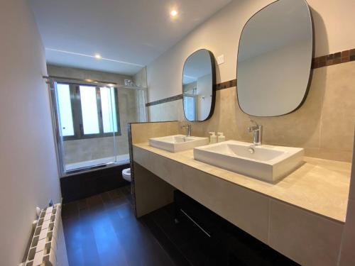 a bathroom with two sinks and a large mirror at Housingcoruña Apartamento Playa Miño 03 in Miño