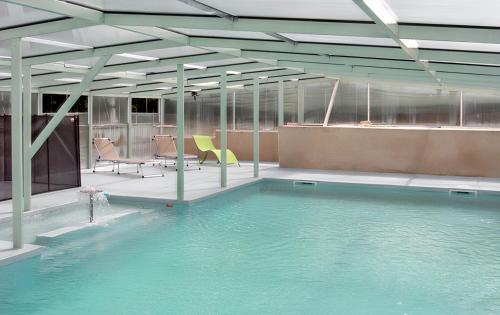 une piscine avec des chaises dans un immeuble dans l'établissement Maison charmante avec piscine partagée à Moncoutant, à Moncoutant