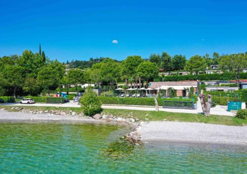 a body of water with trees and a park at Concept Village Piccola Gardiola in San Felice del Benaco