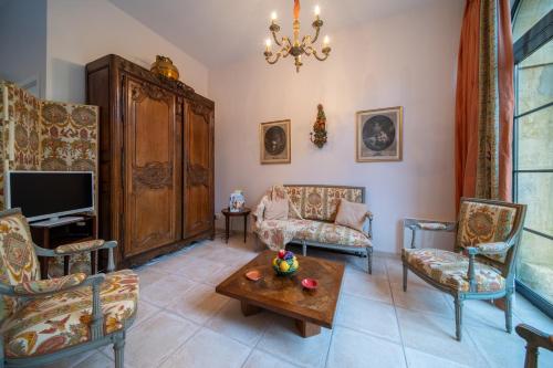 a living room with chairs and a table and a tv at Les calèches de l'Hôtel de Beaumont in Valognes
