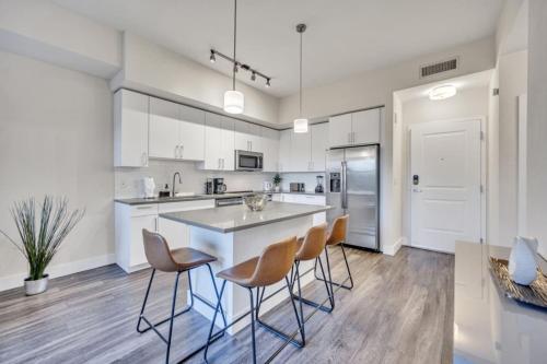 a kitchen with white cabinets and a island with stools at Trendy One Bedroom Getaway Steps from Biscayne in Miami