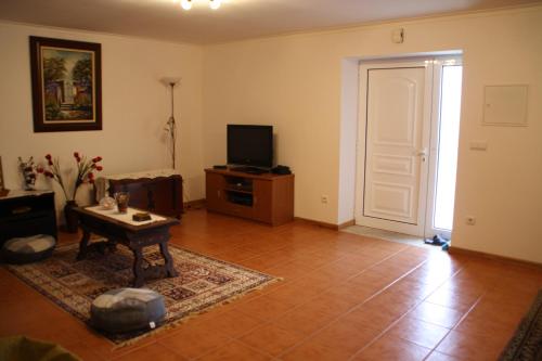 a living room with a table and a tv and a door at Castelo dos Sonhos in Valadares