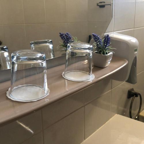 two glass vases sitting on a counter in a bathroom at Káptalan vendégház in Balatonalmádi