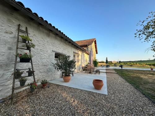 une maison avec des plantes en pot sur une terrasse en gravier dans l'établissement Les Cabrolles, à Saint-Philippe-du-Seignal