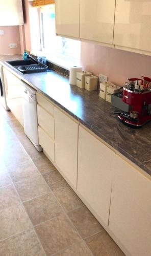 a kitchen with white cabinets and a black counter top at Sowena Contractor Stays - Cleethorpes in Grimsby