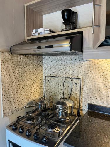 two pots and pans on a stove in a kitchen at Mandala Apartments 2 ambientes in Luque