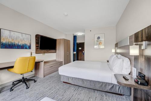 a hotel room with a bed and a desk and a yellow chair at Holiday Inn Express Hotel & Suites-Edmonton South by IHG in Edmonton