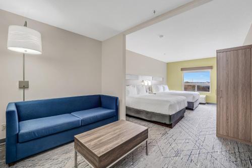 a hotel room with a bed and a blue couch at Holiday Inn Express Hotel & Suites-Edmonton South by IHG in Edmonton