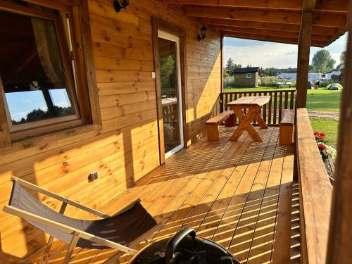 a wooden cabin with a bench and a table on the porch at Domek 4-6osobowy in Wroceń