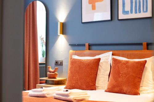 a bedroom with a bed with orange and white pillows at Gillis Eight Guest Rooms by Romy&Travis in Bruges