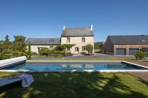 une maison avec une piscine en face d'une cour dans l'établissement Manoir de la Nogrie - Chambre de charme avec accès privatif - Piscine chauffée sur domaine 5 étoiles, à Val-dʼIzé
