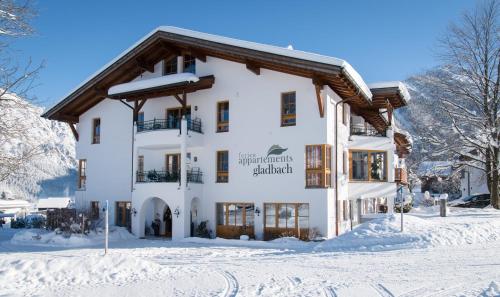 a large white building in the snow at Appartements Gladbach in Heiterwang