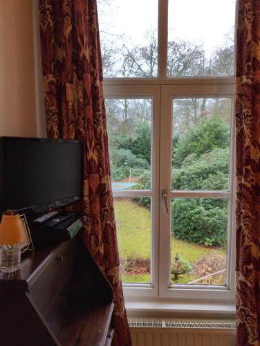a room with a large window with a television at Eremyten Hof in Evergem