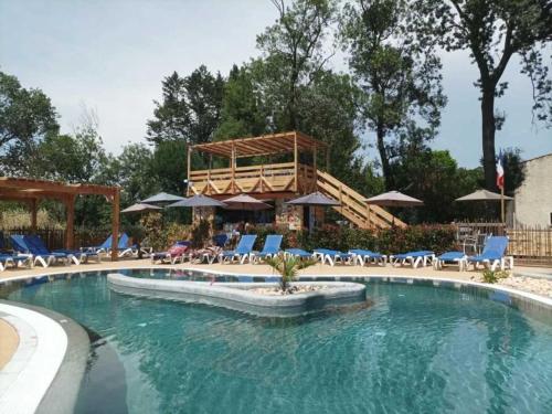 une piscine avec chaises et parasols dans un complexe hôtelier dans l'établissement Camping 3 étoiles - Piscine - eeebcb, à Roquebrune-sur Argens