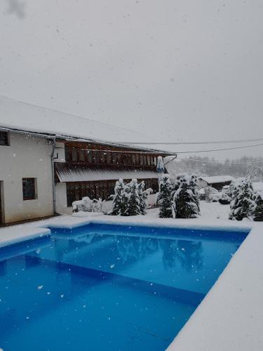 a swimming pool covered in snow with a building at Pensiunea Andreea in Mărgineni