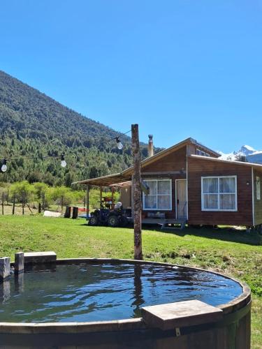 a house with a pond in front of it at Cabañas y tinaja El bus de chaqueihua in Hornopiren
