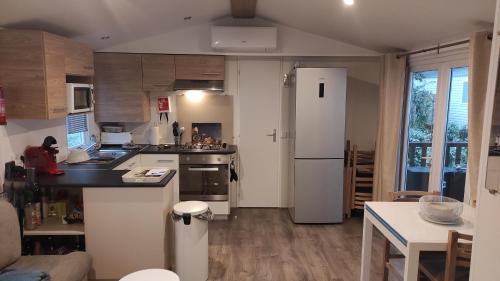 une cuisine avec un réfrigérateur blanc et une table dans l'établissement MOBILHOME Soulac, à Soulac-sur-Mer