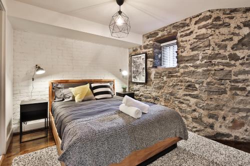 a bedroom with a bed with a stone wall at Les Lofts du Mile End-Plateau Mont Royal in Montréal
