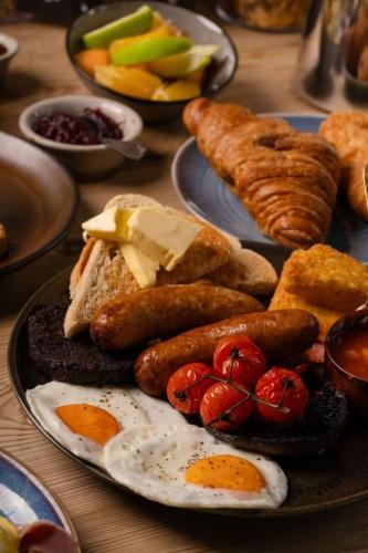a plate of breakfast food with eggs sausage and bread at The Peat Spade Inn in Stockbridge