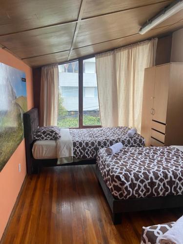 a bedroom with two beds and a window at Blue house La Floresta in Quito