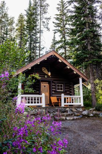 a log cabin in the woods with purple flowers at Storm Mountain Lodge & Cabins in Banff
