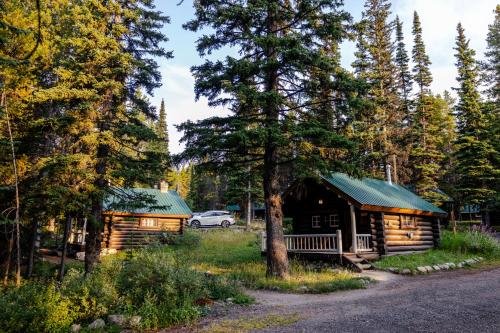 a cabin in the woods with a car parked next to it at Storm Mountain Lodge & Cabins in Banff