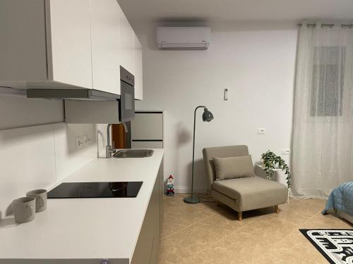 a living room with a chair and a kitchen at Panoramic Condo in Tirana! in Tirana
