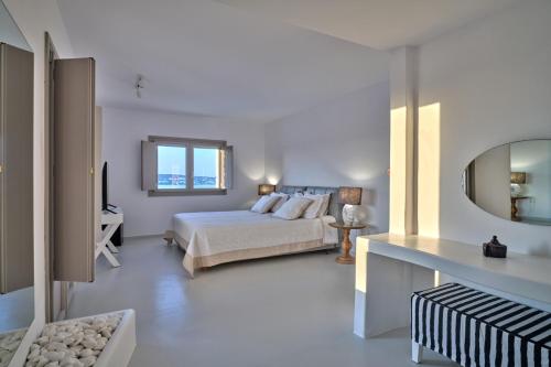 een witte slaapkamer met een bed en een spiegel bij Empire Luxury Villas in Santa Maria