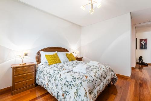 a bedroom with a bed and a dresser with yellow pillows at Casa La Guardia at 5 minutes from the beach in Póvoa de Varzim