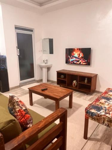 a living room with a tv on a wall at Koselig Studio Apartment with Swimming Pool in Naro Moru
