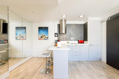 une cuisine avec des armoires blanches et un comptoir avec des tabourets dans l'établissement Cosy & design à côté du Palais et des plages, à Cannes