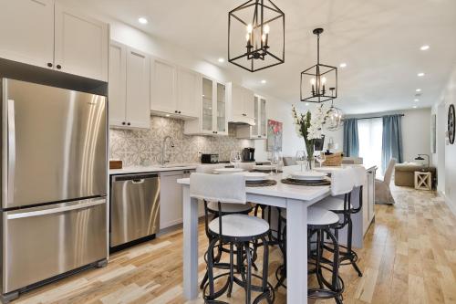 a kitchen with white cabinets and a kitchen island with bar stools at Les Lofts du Mile End-Plateau Mont Royal in Montréal