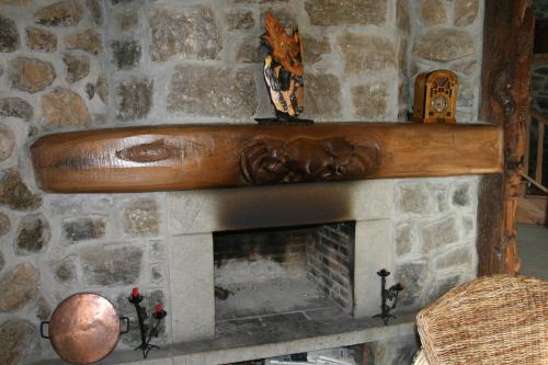 a stone fireplace with a wooden mantle above it at El Quesar de Gamoneo in Gamonedo de Cangas