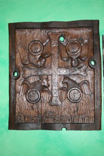 a wooden cross with angels andorns on a wall at El Quesar de Gamoneo in Gamonedo de Cangas